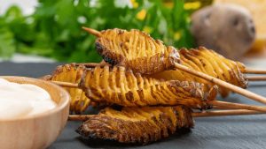 Unas papas negras acordeón servidas con salsa